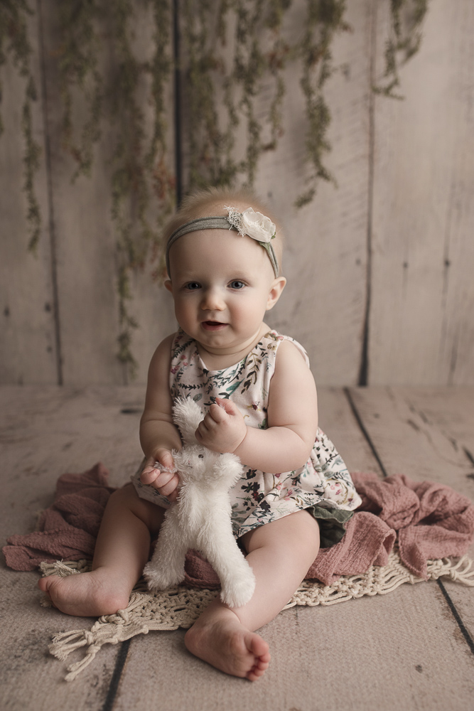 Playing with a cute bunny at her milestone session with her Lafayette Indiana baby photographer.