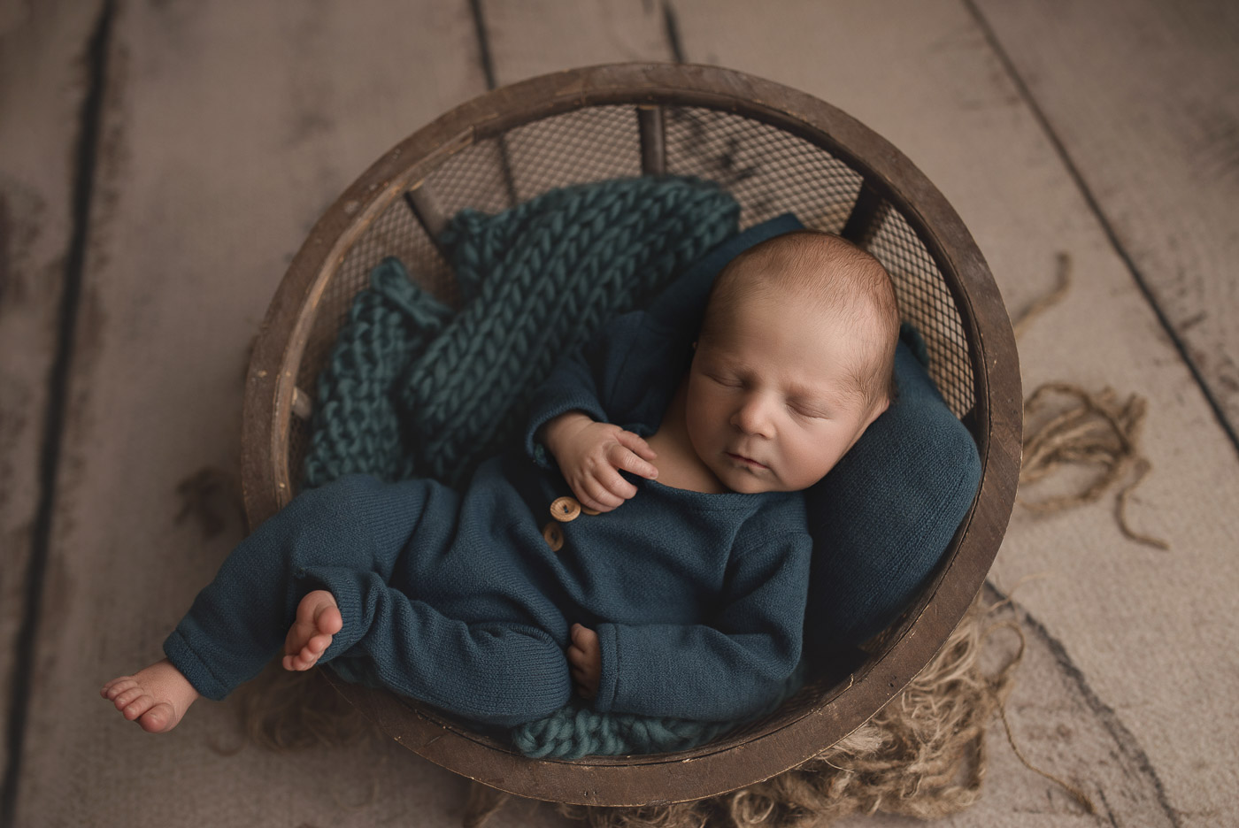 Little baby boy posed in a bowl at his cute newborn session.