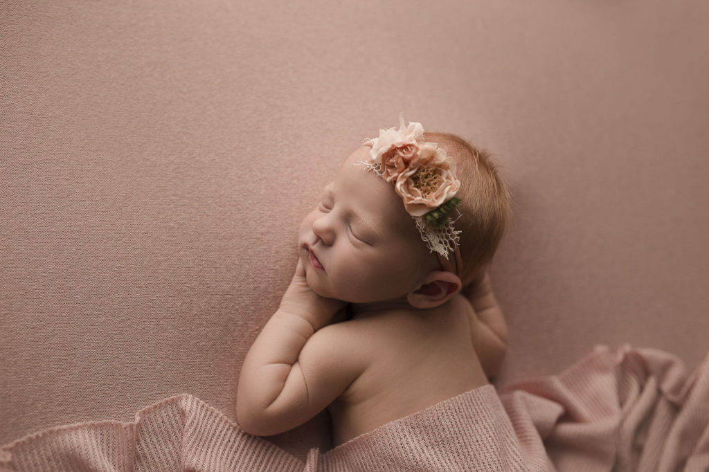 Cute baby girl wearing a pretty headband at her newborn photography session.