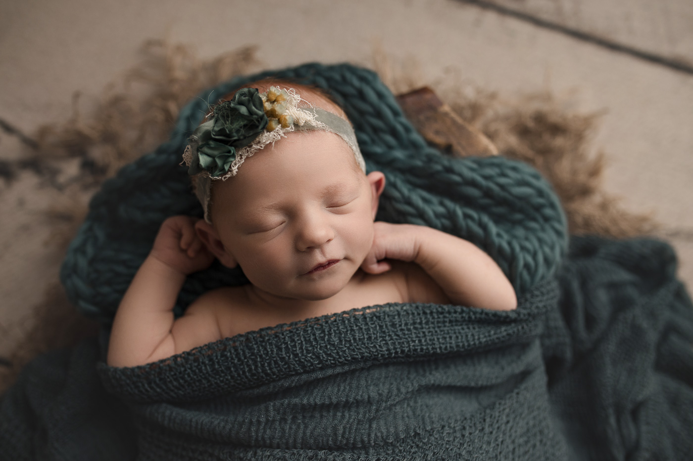 Newborn girl in a wooden trench with a pretty teal wrap in Lafayette Indiana.