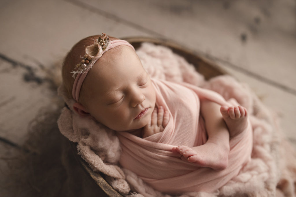 Gorgeous baby girl in a bowl at her newborn photography session.