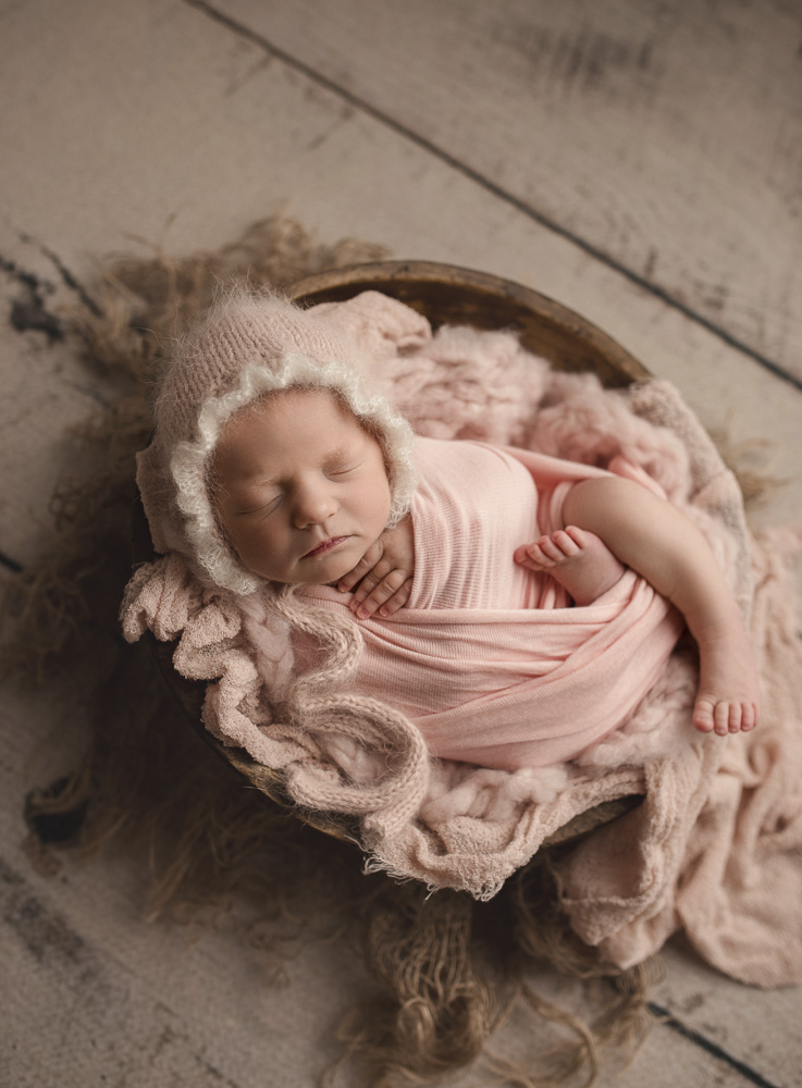 Baby girl wearing a pretty pink bonnet in her newborn pictures.