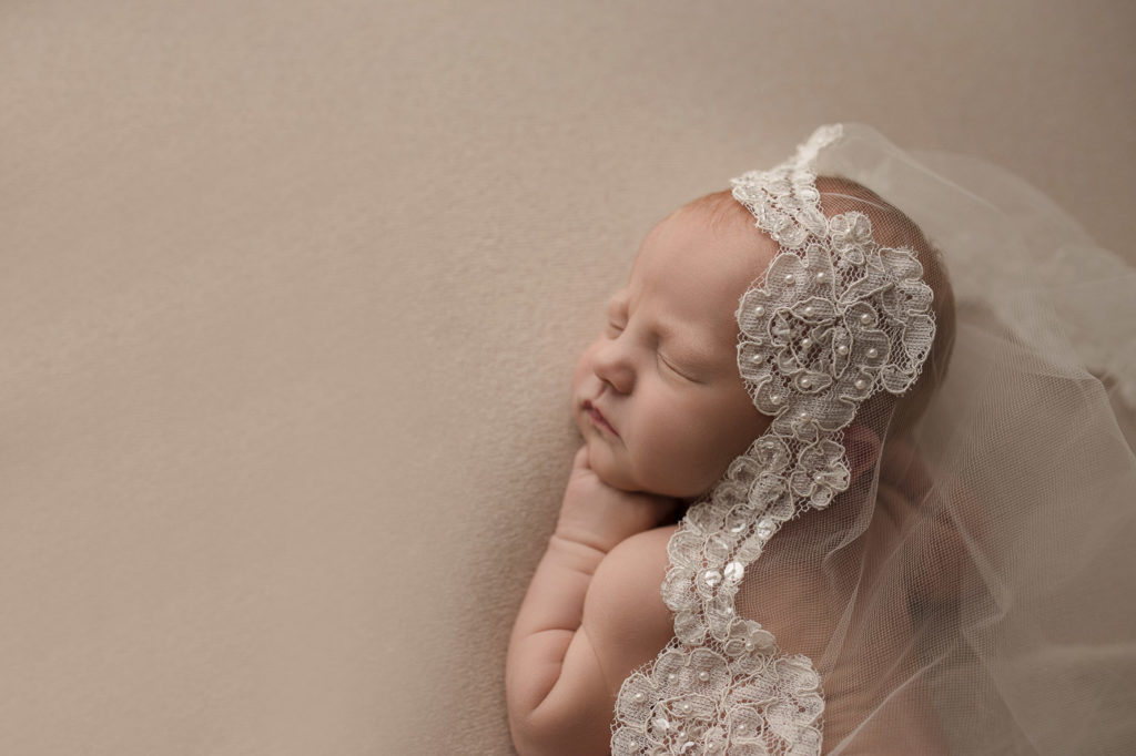 Adorable newborn girl posed with her mom's wedding veil in Lafayette Indiana.