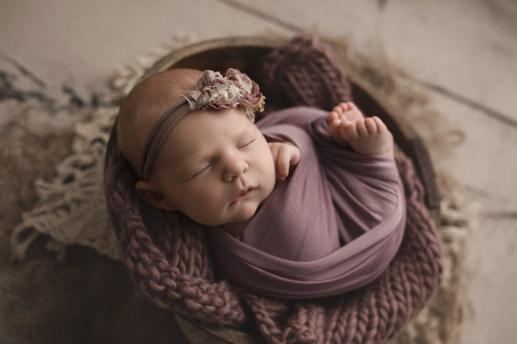 Cute newborn girl posed in a bowl wrapped up at her newborn session in Lafayette.
