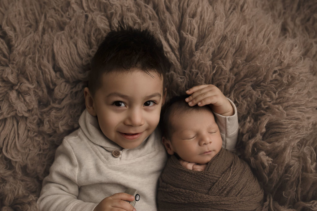 Big brother posing with his new sibling at a Lafayette Indiana newborn session.