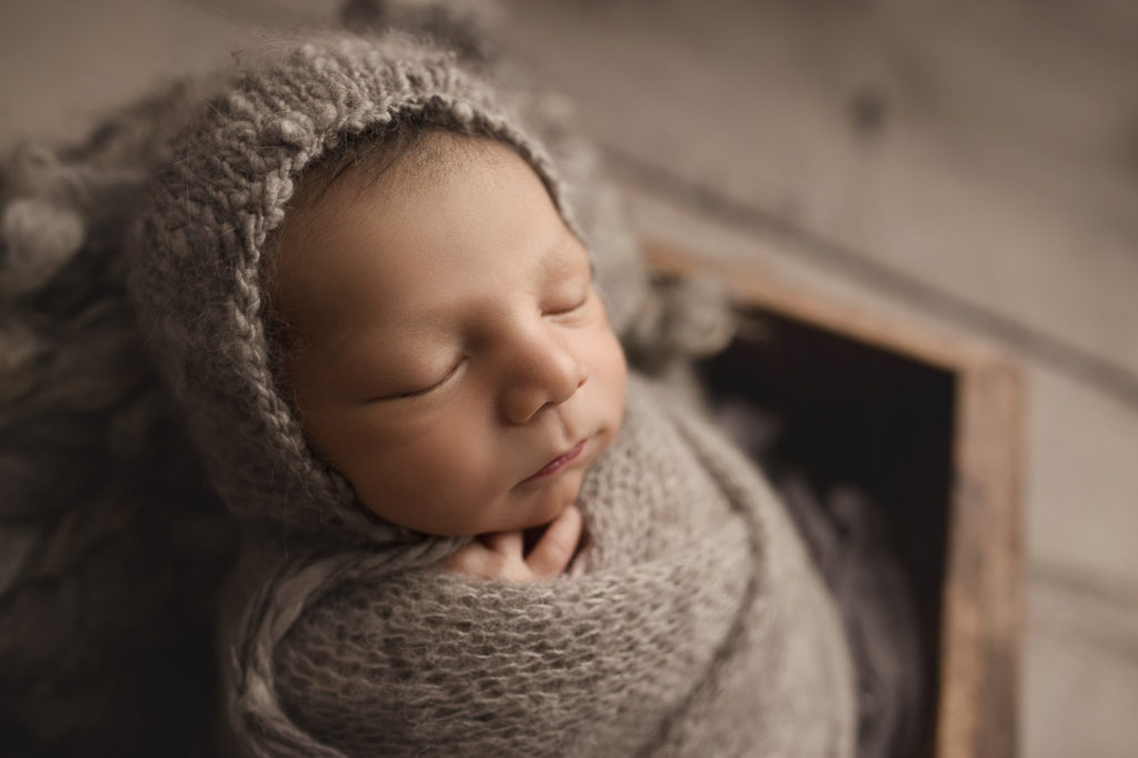 Baby boy wrapped in grey at a newborn session.