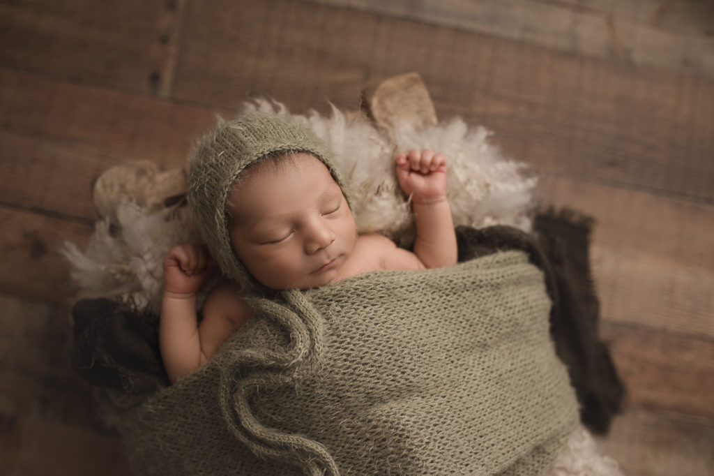 Little cute baby boy in green wrap at his newborn session.