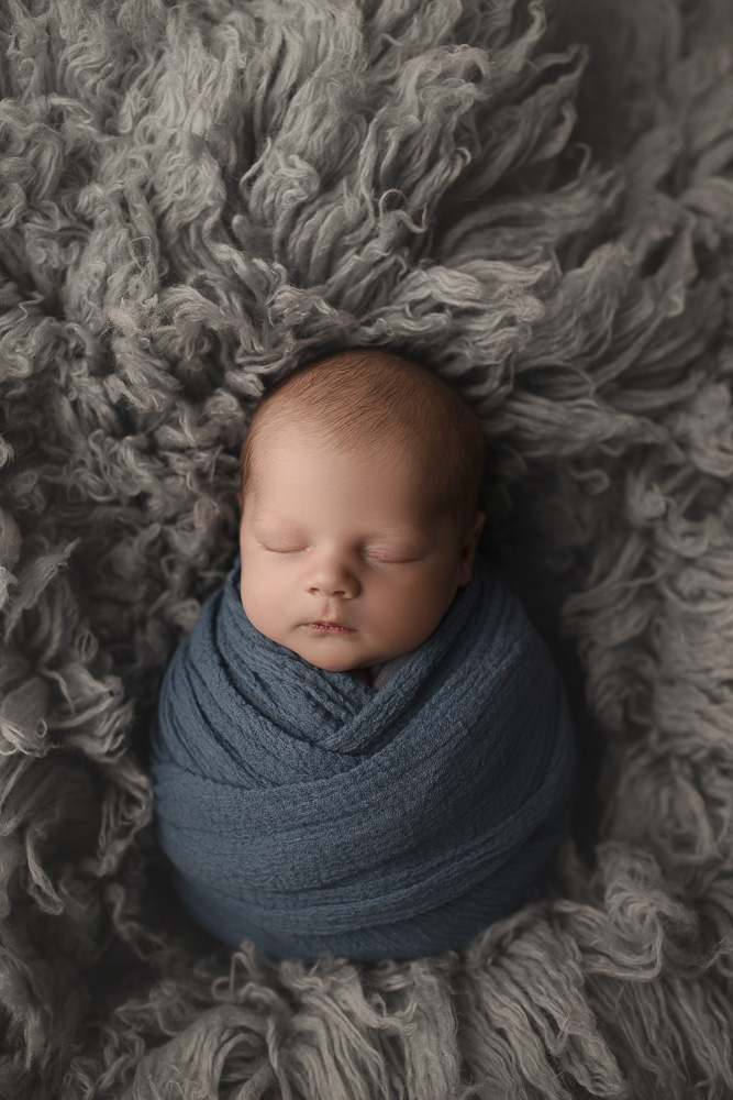 Adorable sleeping baby at his newborn session posed on a flokati.