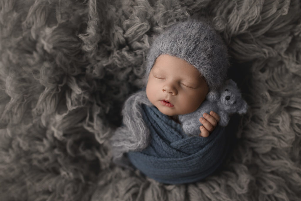 Sweet boy snuggling with a little teddy bear at his newborn session.