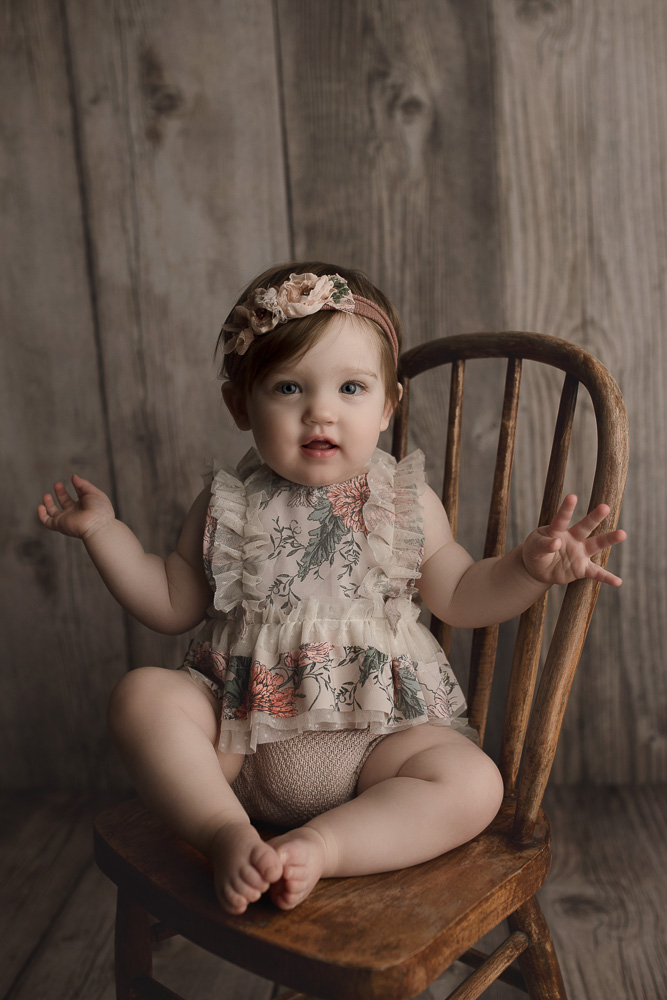 Sweet baby girl sitting in a wooden chair at her one year session in Indiana.