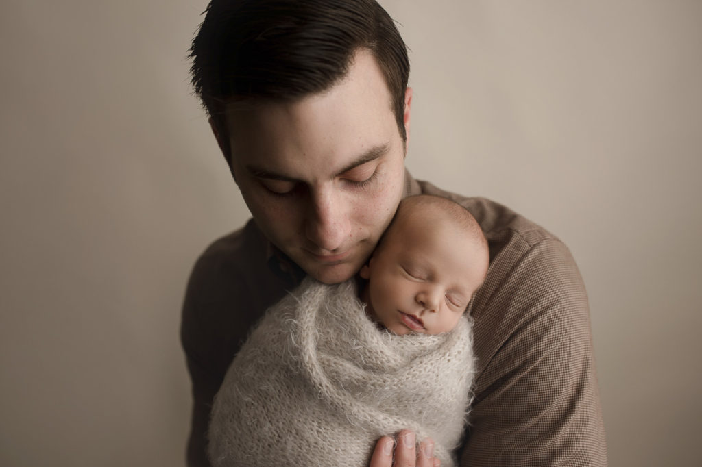 Dad posed with baby boy at a studio newborn session in Indiana.