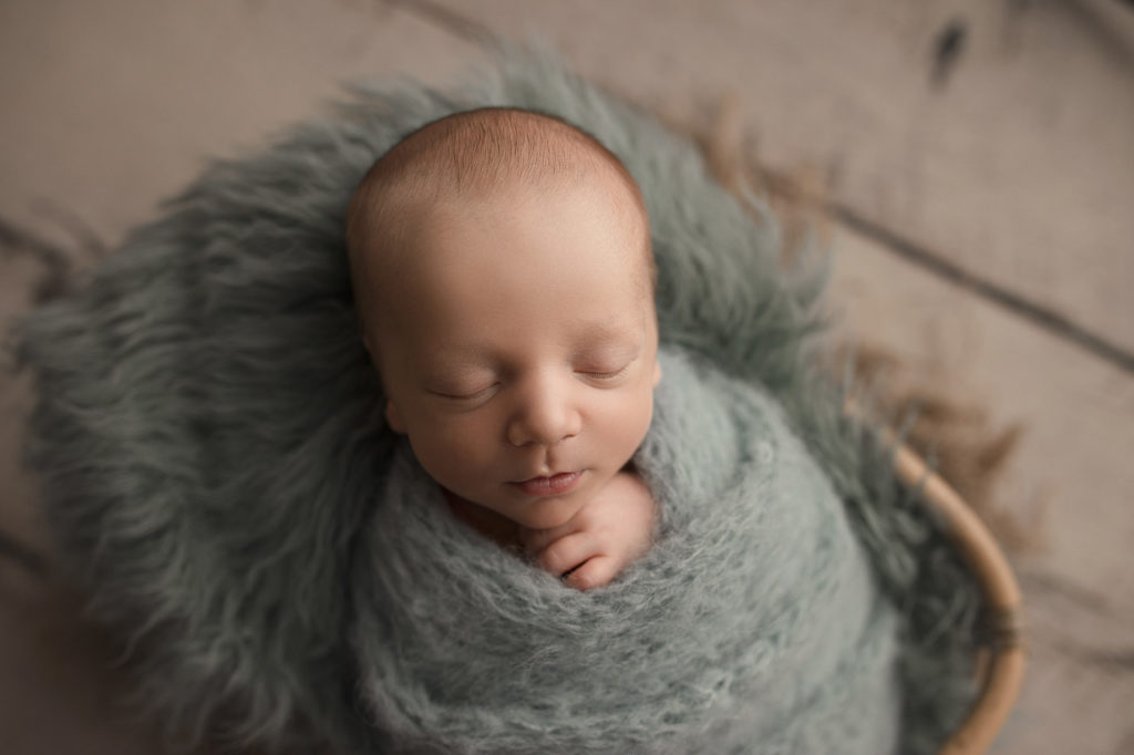 Baby boy wrapped for his newborn session pictures.
