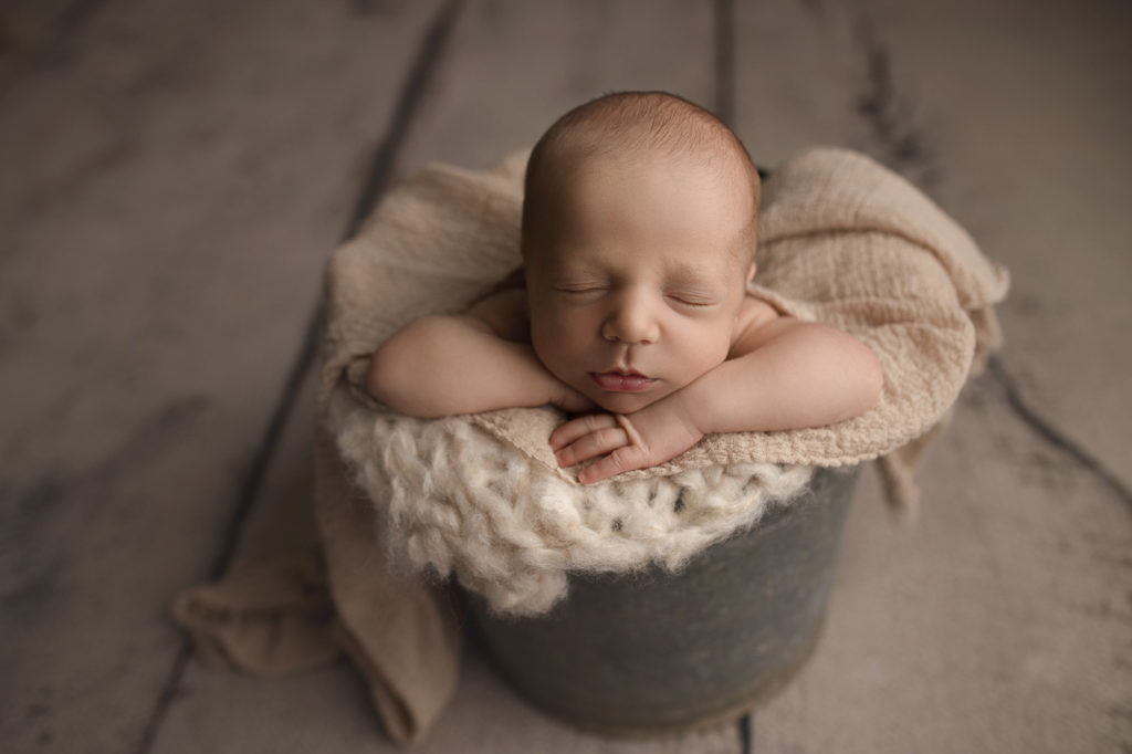 Little baby boy posed in a bucket during his newborn session.