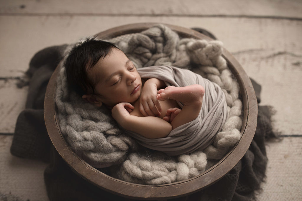 Cute baby posed in a bowl during a studio newborn session.