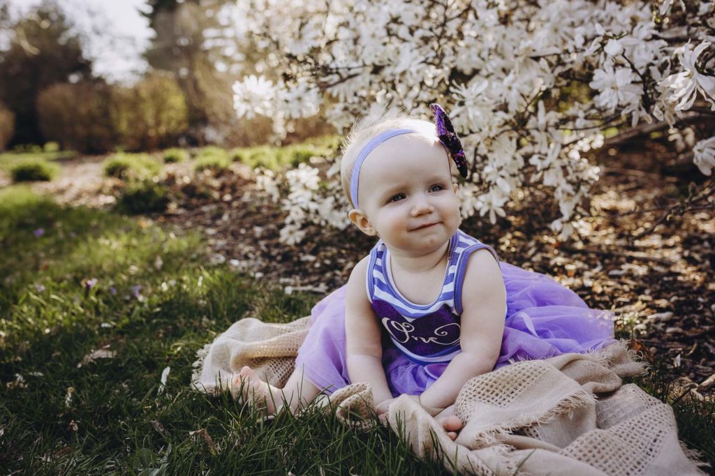 Cute little girl in a purple dress outside at her milestone session in West Lafayette.