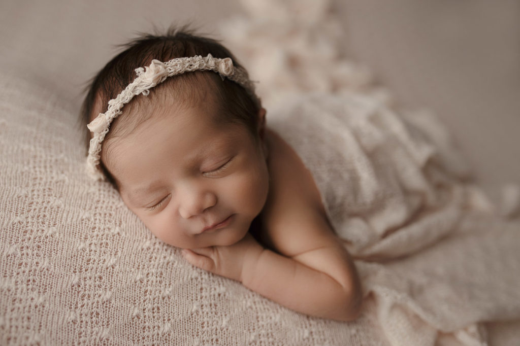 Newborn girl posed on a pretty lace backdrop at her newborn session in Lafayette Indiana.