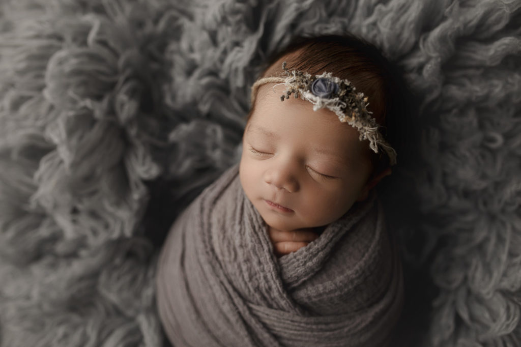 Baby girl all wrapped up with a cute delicate headband for her newborn session in Lafayette Indiana.