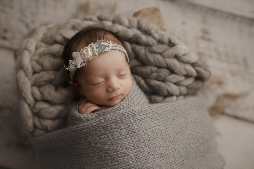 Sleeping like an angel wrapped in a soft grey wrap during her newborn session.
