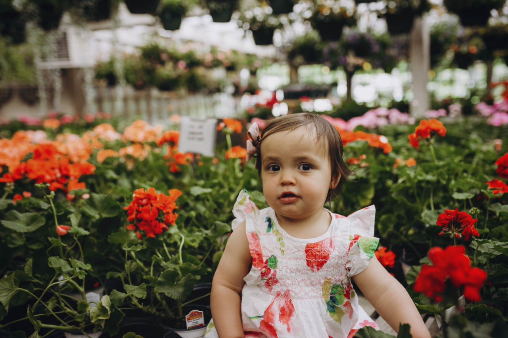 Cute girl sitting in the flowers at a greenhouse in Brownsburg Indiana.