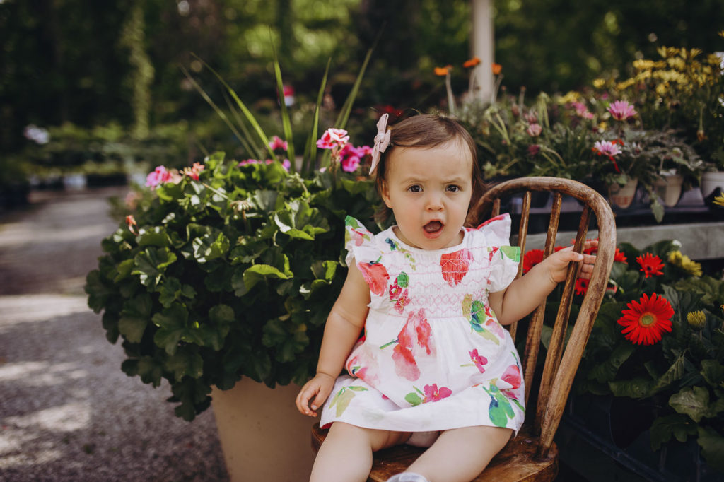 Little girl sitting on a chair in a garden.