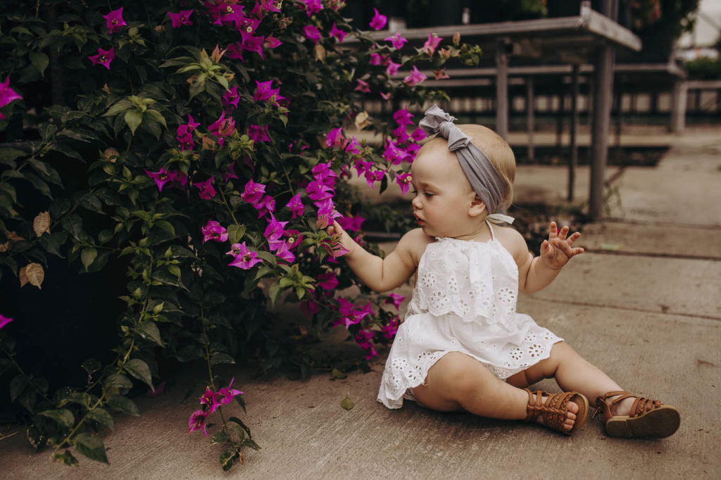 Little girl looking at flowers during her photography session.