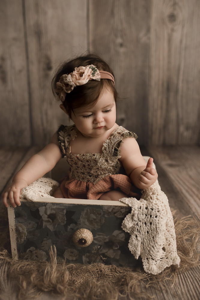 Baby girl posed in a wooden crate with a lace layer.