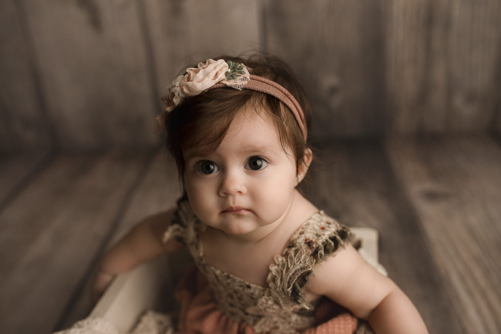Close up image of cute baby girl's face during her sitter milestone session in a Lafayette studio.