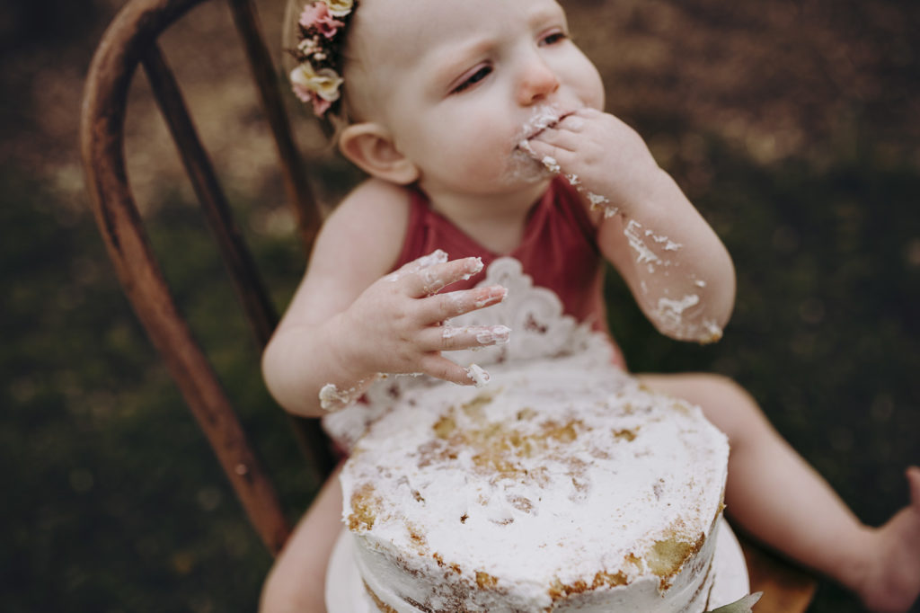 Eating cake with white icing at her milestone session.