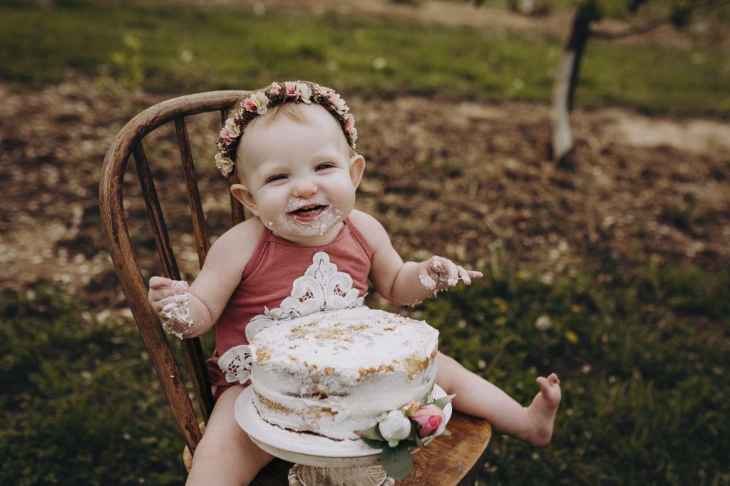 Little girl with floral halo smiling at her birthday milestone session at Wea Orchard in Lafayette Indiana.