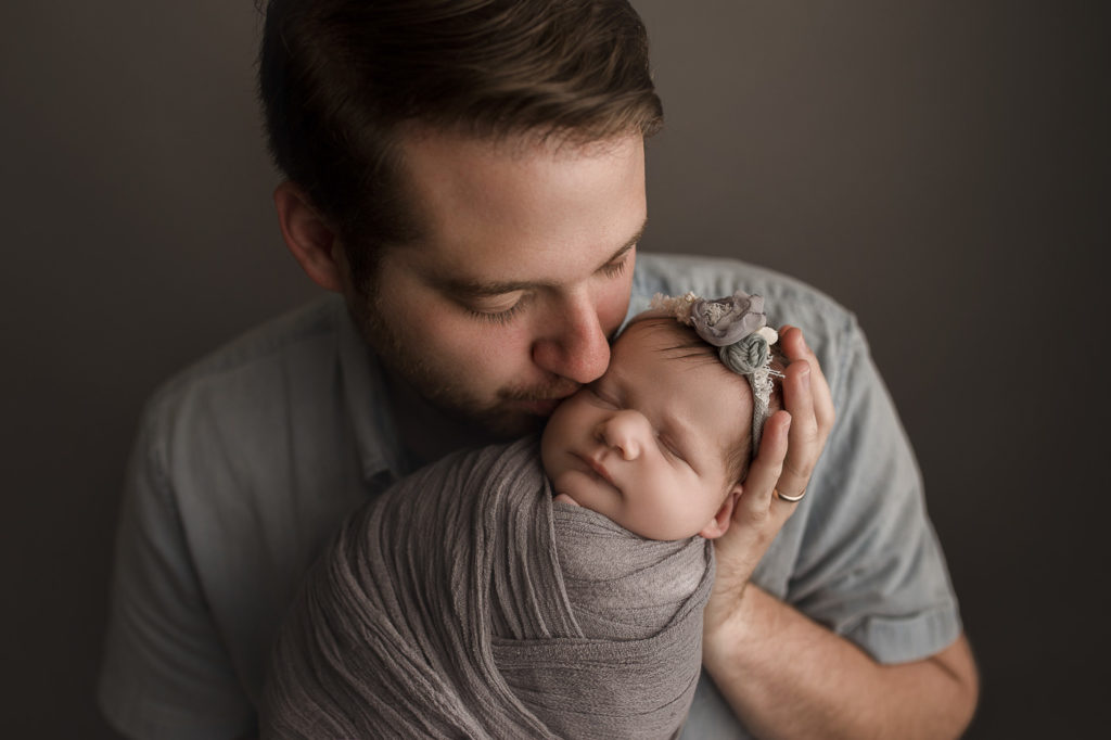 Dad holding sweet baby girl for newborn studio session.