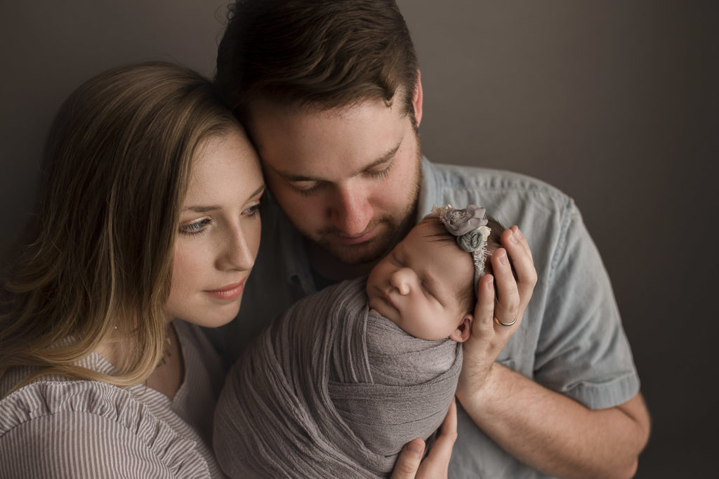 Parents looking at sweet baby sleeping during newborn session.