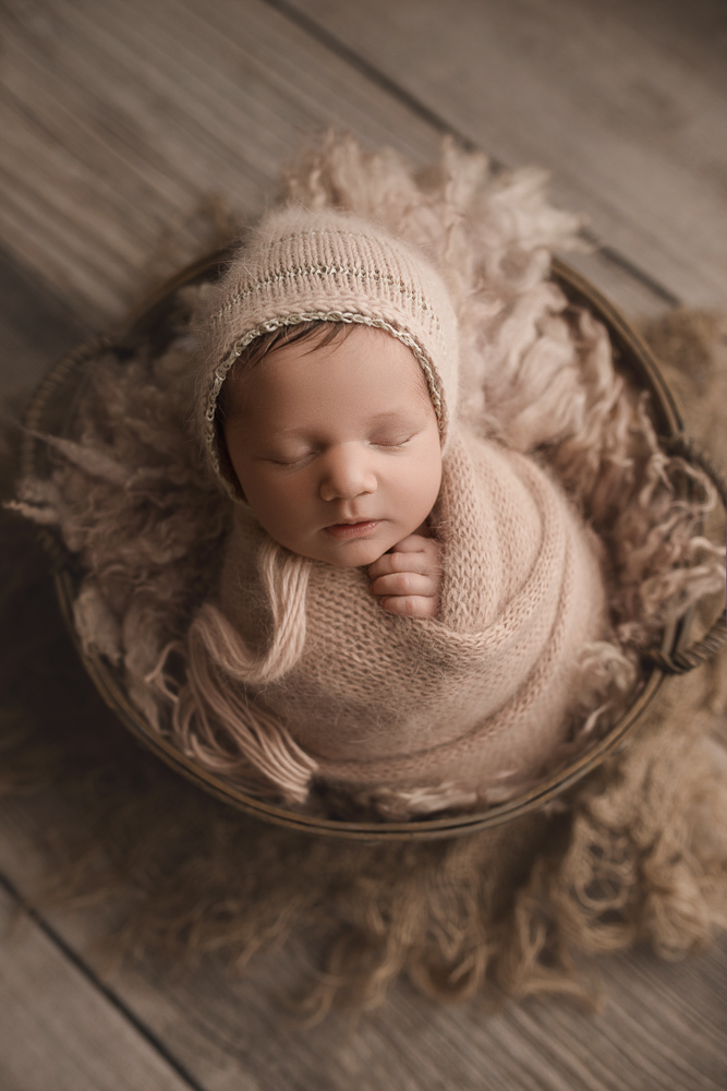 Baby with bonnet in basket for newborn session in Lafayette Indiana.