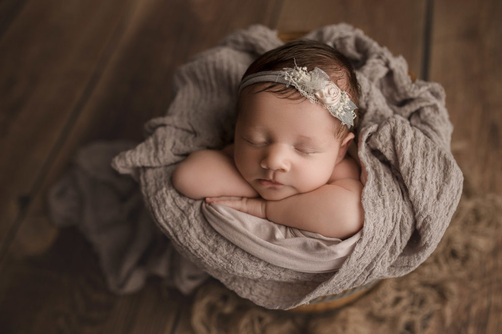 Cute girl in a wooden bucket for her newborn session in Lafayette Indiana.