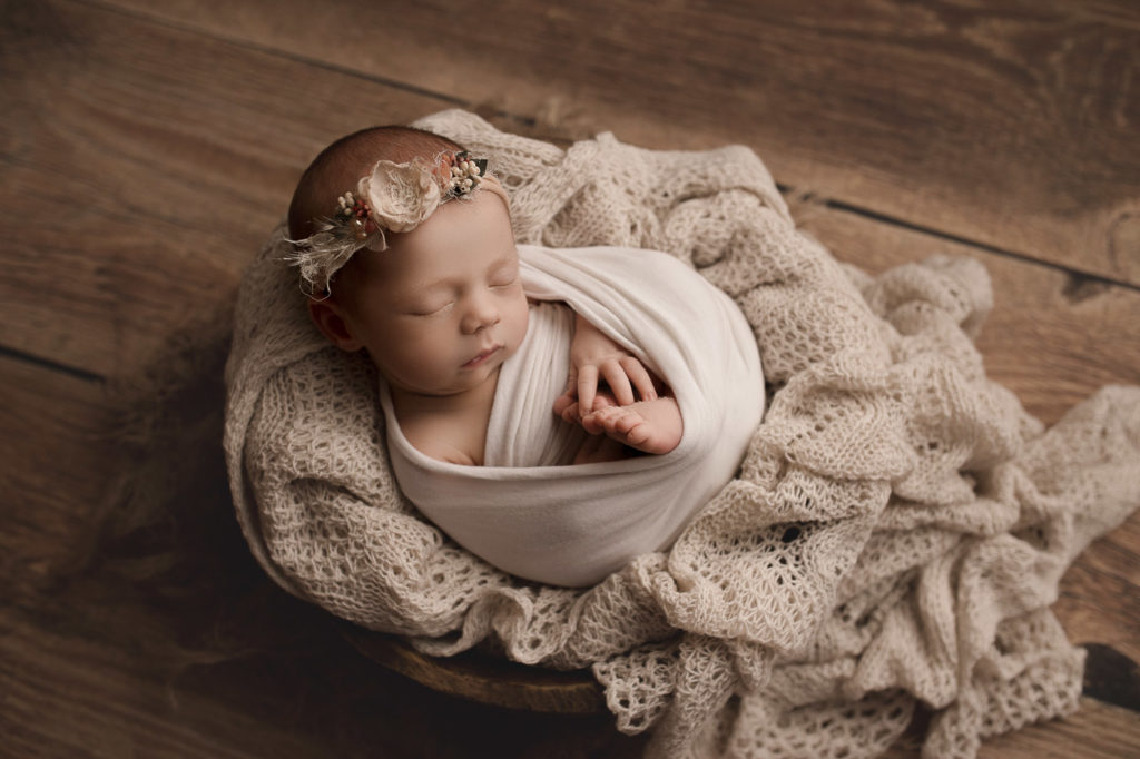 Posed newborn in wooden bowl.
