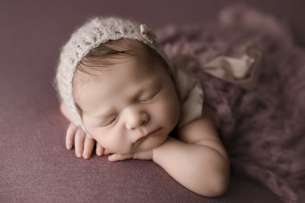 Adorable sleepy baby girl wearing a cute bonnet at her newborn session.