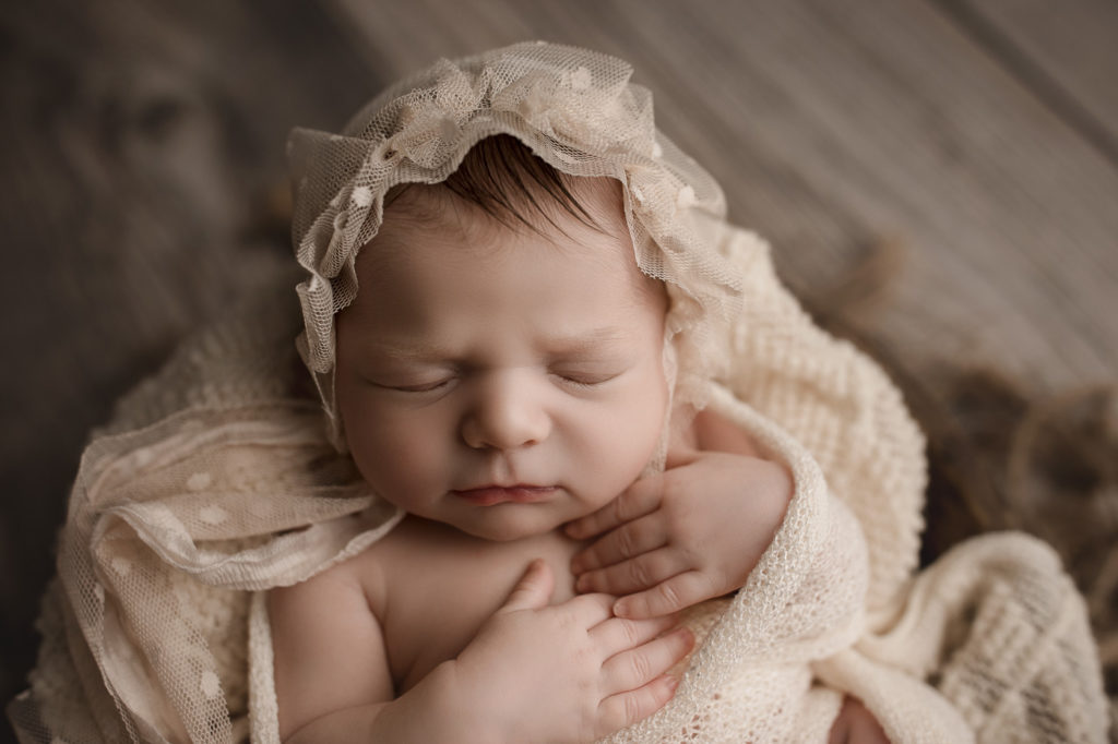 Adorable cream bonnet on a sweet newborn girl at her studio newborn session in Lafayette Indiana.