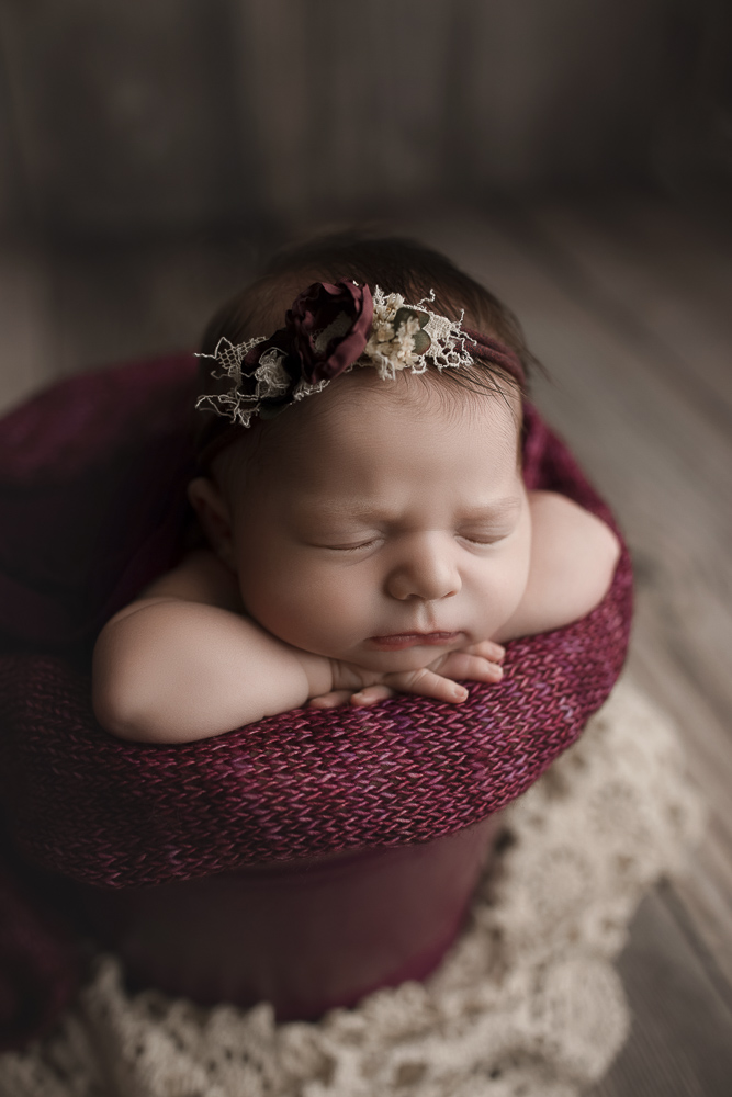 Cute newborn girl sleeping in a bucket at her photography session.