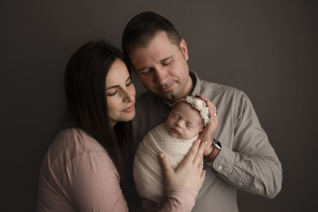 Adorable parents welcoming their new baby girl posed at a studio newborn session in West Lafayette Indiana.
