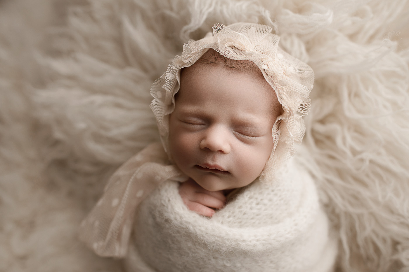 Pretty baby girl wearing a cute bonnet during her studio newborn session.