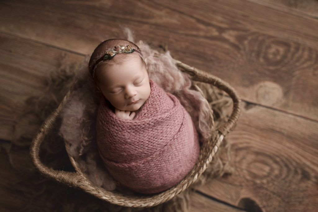 Cute baby girl posed in a rustic basket for her newborn session in West Lafayette.