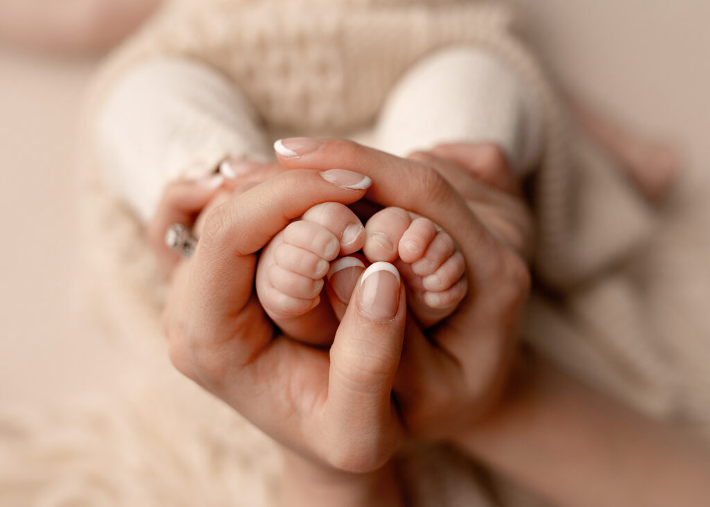 Precious close up shot of a newborn baby's feet being held by mom's hands.