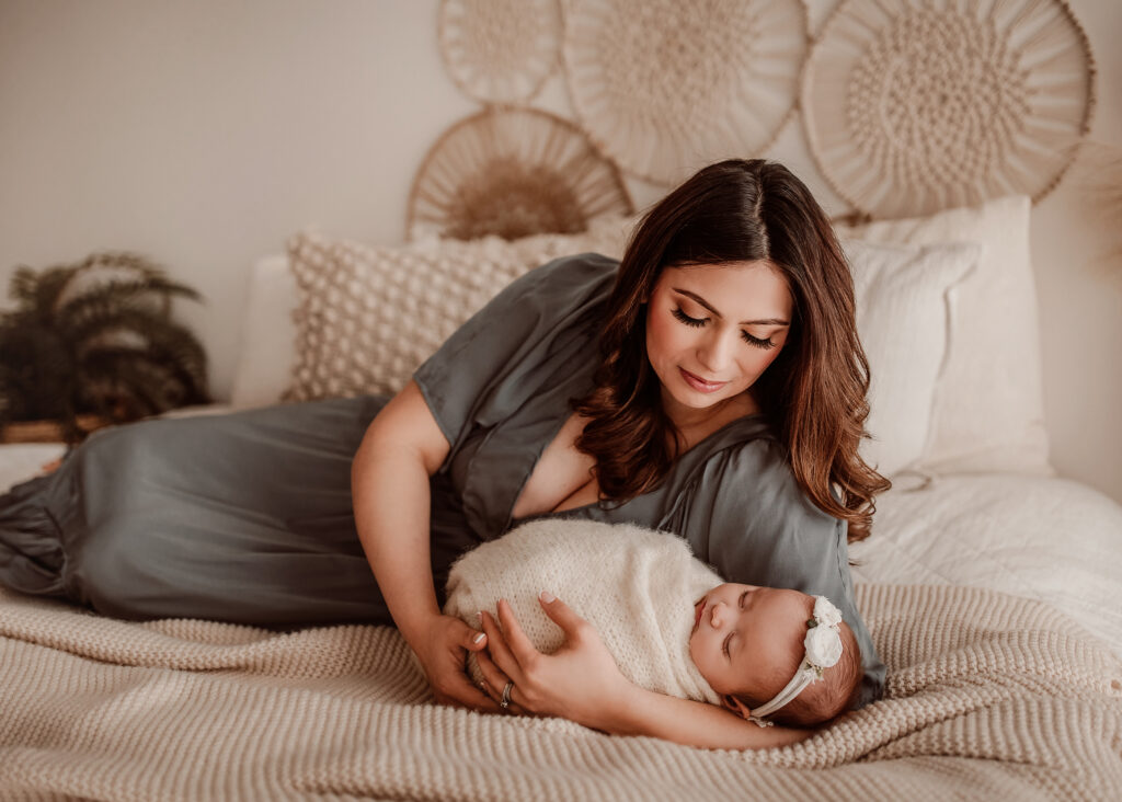 Mom smiling down at newborn baby girl at her studio session.